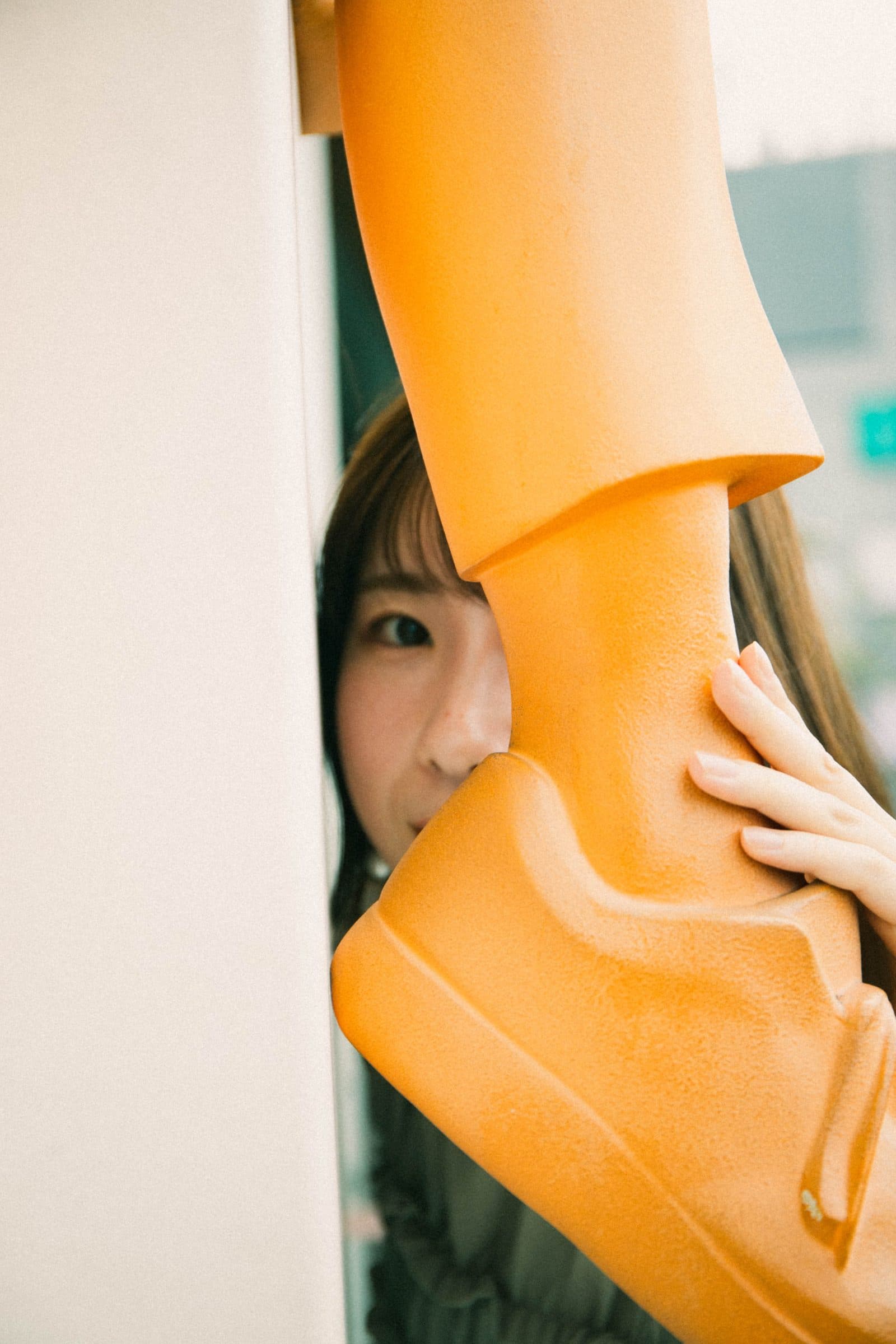 オレンジのオブジェ越しにのぞく女性