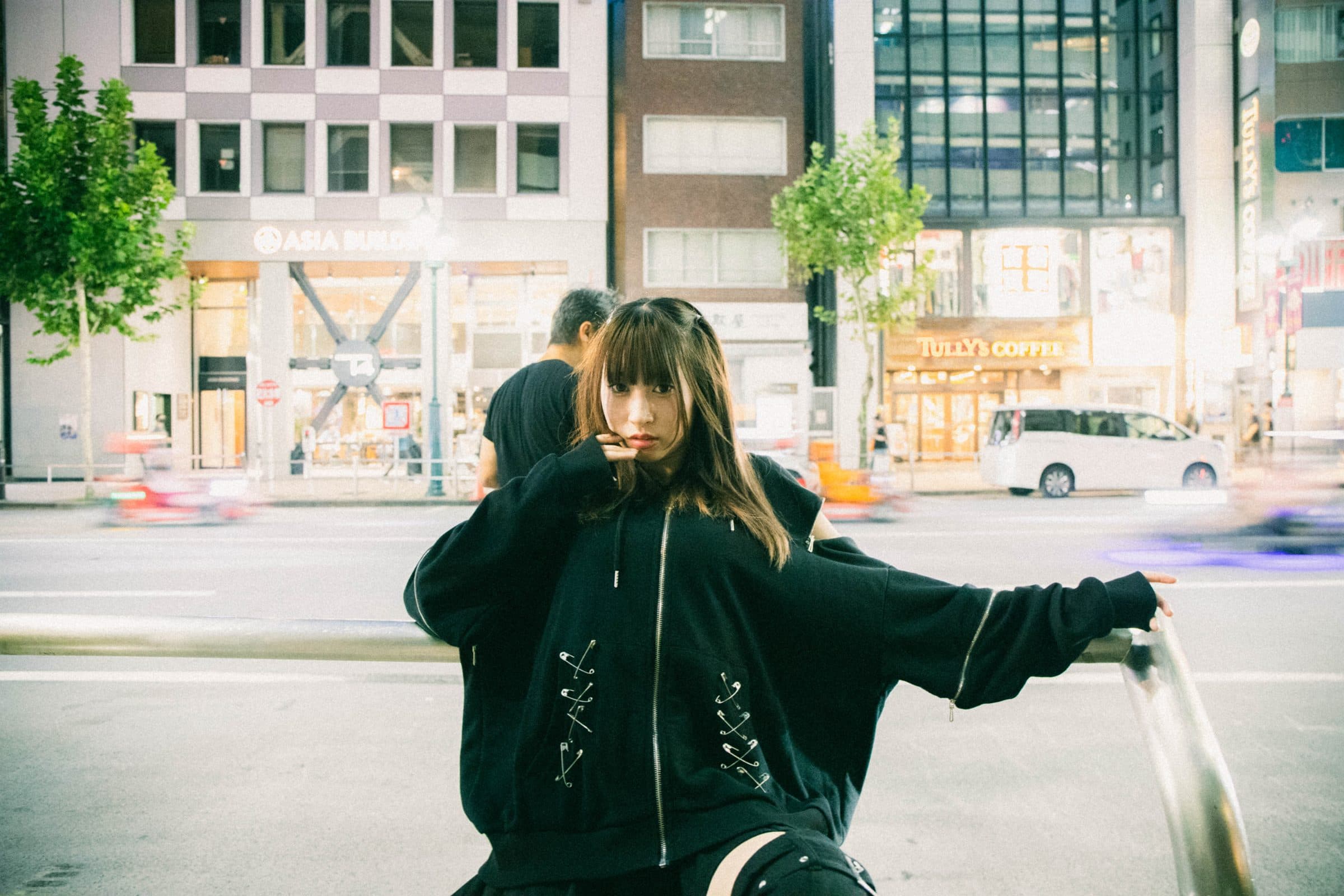 夜の街のガードレールに腰掛ける女性のポートレート